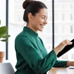 예방의학 세미나 준비 체크리스트 - A cheerful woman in her late 30s sits at a bright, modern desk, actively reviewing a digital health ...